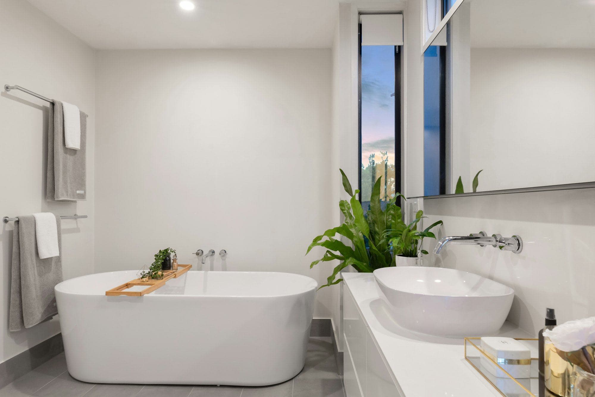 White bathroom with a bath and a large-leaf plant by the window